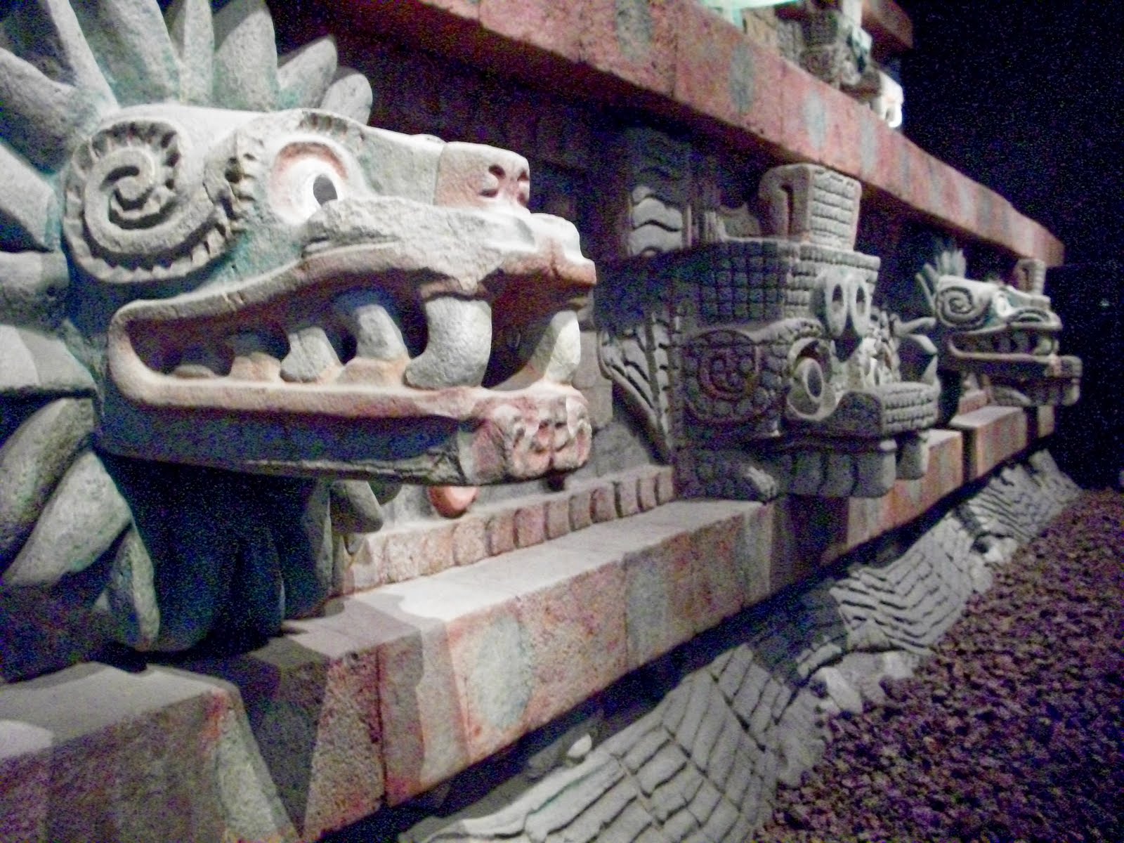 Large Aztec building with statues and faces incorporated into the structure.